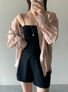 Person in a black camisole and shorts with an oversized shirt and silver necklace