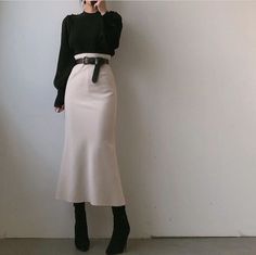 Person in a black sweater and midi skirt with a black belt and boots