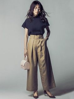 Woman in wide leg pants and a dark top holding a small handbag