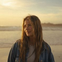 Woman with long hair in a denim jacket on a beach at golden hour