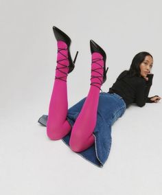 Woman in pink tights and black heels lying on a white studio floor