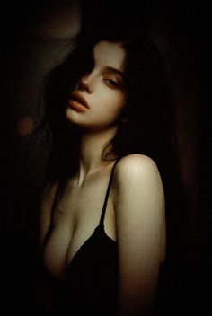 Woman with dark hair in a black bra with dramatic lighting and film grain