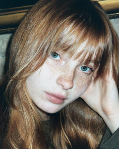 Close up portrait of a person with red hair, freckles, and blue eyes