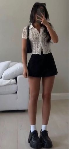Person in a white lace top and black mini skirt taking a mirror selfie