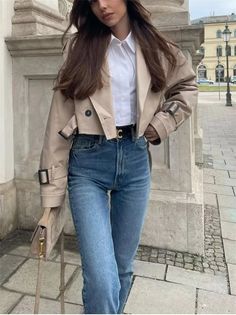 Woman in a cropped jacket, white shirt, and blue jeans on a street