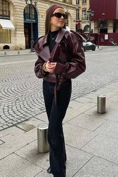 Woman in a burgundy leather jacket and black jeans on a city street