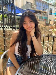 Young woman with long hair sitting at an outdoor table in daylight