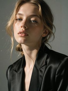 Woman with blonde hair and freckles wearing a black blazer with soft lighting
