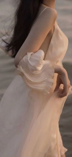 Woman in a light dress with ruffled sleeves and long dark hair outdoors