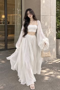 Woman in a white crop top, maxi skirt, and sheer sleeves outdoors