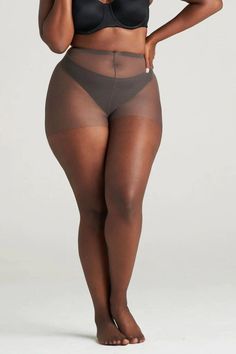 Woman in a black bra and sheer tights posing in a studio