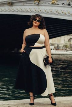 Woman in a black and white yin yang pattern outfit standing by water