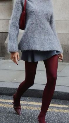 Person in a gray sweater, mini skirt, and red tights walking on a street