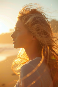 Woman with blonde hair backlit by the setting sun on a beach