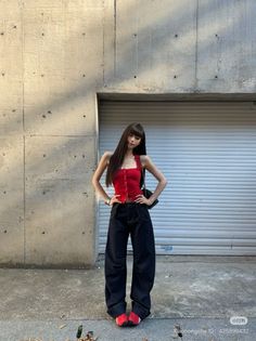 Woman with long hair wearing a red top and baggy jeans outdoors