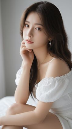 Woman with long hair in a white off-shoulder dress, looking at the camera