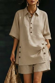 Woman in a beige linen shirt and shorts holding a straw bag