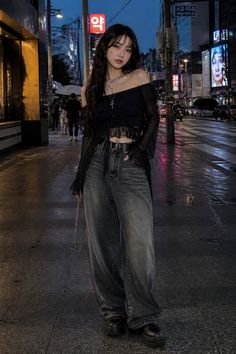Woman in an off-shoulder top and wide-leg jeans on a city street at night
