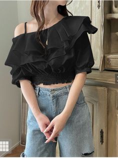 Woman in a black ruffled off-shoulder top and blue jeans indoors