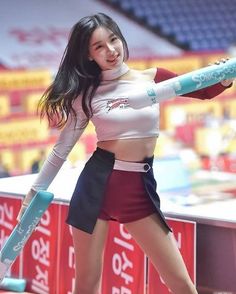 Woman in a cheerleader uniform holding inflatable sticks at an athletic event