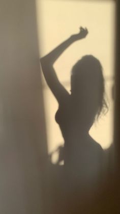 Silhouette of a woman with long hair and curvy body posing indoors