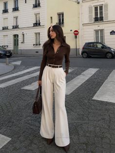 Woman in a brown top and wide leg pants standing on a city street