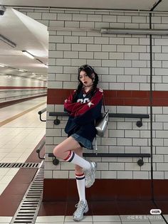 Woman with pigtails in a varsity jacket and denim skirt in an underground tunnel