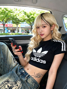 Woman with blonde hair and a crop top sitting in a car