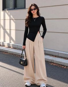 Woman with long hair and sunglasses wearing a black top and wide leg pants