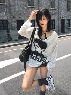 Woman with black hair wearing an oversized shirt and shorts on a street