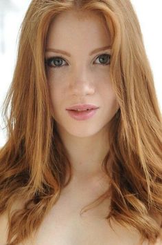 Close-up portrait of a woman with long red hair and green eyes