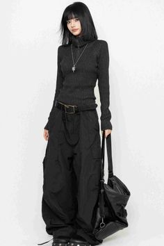 Woman in a black turtleneck and baggy pants holding a black bag