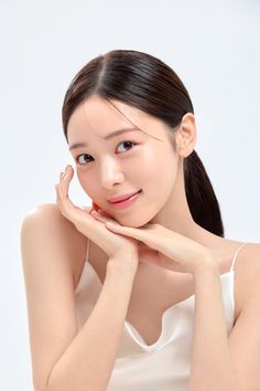 Woman with a ponytail in a white top, hands cupping her face