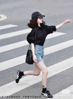 Woman in a black shirt and denim shorts walking on a crosswalk