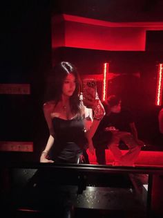Woman in a strapless top taking a mirror selfie in a nightclub with red lighting