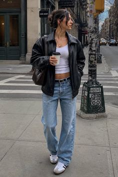 Woman in a black leather jacket and white crop top on a city street