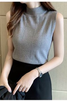 Woman in a gray sleeveless top and black skirt with a silver watch