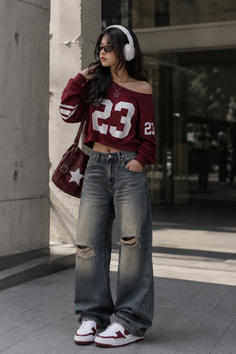 Woman in a crop top and ripped jeans with headphones and sunglasses outdoors