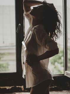 Woman in a white shirt posing by a window with strong backlight