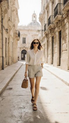 Woman in a white shirt and shorts walking down a narrow street