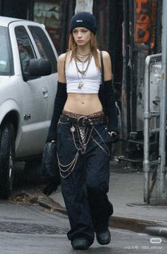 Woman in a crop top, baggy pants, and beanie walking on a street