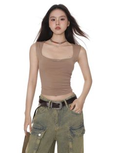Woman with long hair wearing a crop top and cargo pants with a western belt