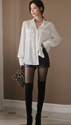 Woman in a white shirt, black shorts, and thigh high boots holding a leopard print bag