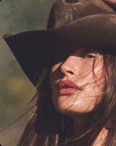 Woman wearing a cowboy hat with dramatic lighting casting shadows on her face