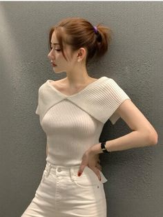 Woman in a white off-shoulder top and white pants with a ponytail