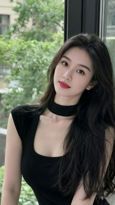 Woman with long black hair and a black top with a choker, looking at the camera
