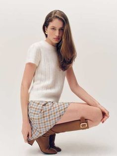 Woman with long hair wearing a plaid skirt and knee-high boots in a studio