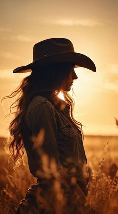 Woman in a cowboy hat and denim jacket in a field at golden hour