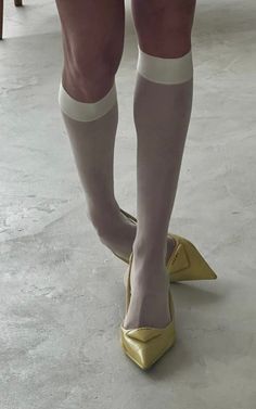 Person wearing white socks and yellow pointed heels on a light-colored floor
