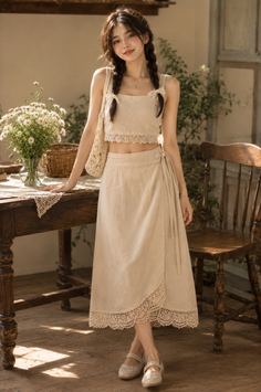 Woman with braids wearing a crop top and midi skirt with lace trim indoors
